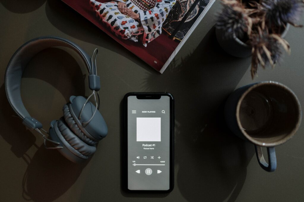 Uno smartphone su cui è visualizzata la schermata di un podcast con accanto delle cuffie